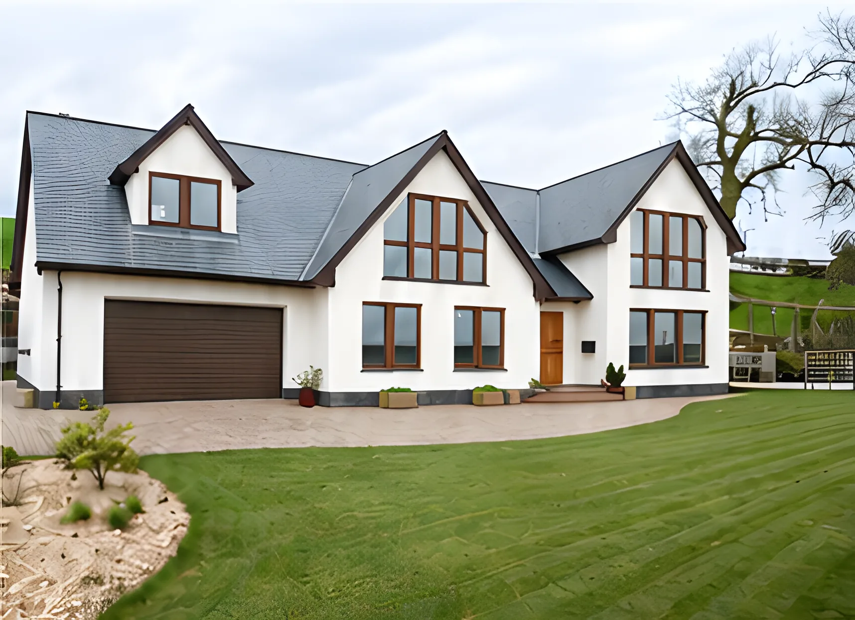 White detached house with a slate roof, timber-framed windows, a dark garage door and a freshly laid lawn