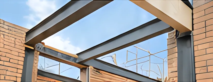 Steel beams set into new brickwork against a blue sky